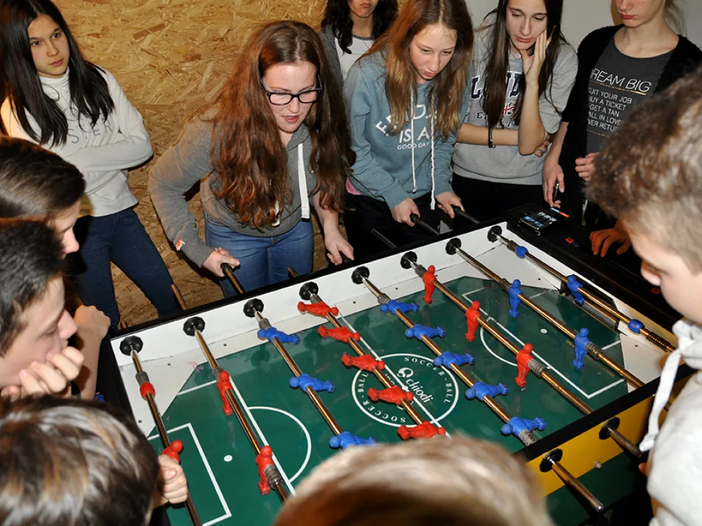 Gruppe drängt sich lachend um den Tischfußballtisch.